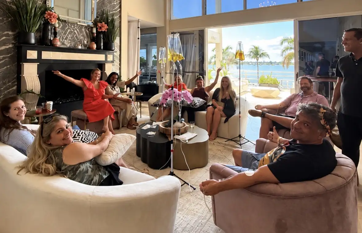 A group smiling and relaxing in a waterfront living room while receiving IV therapy from The IV Pro